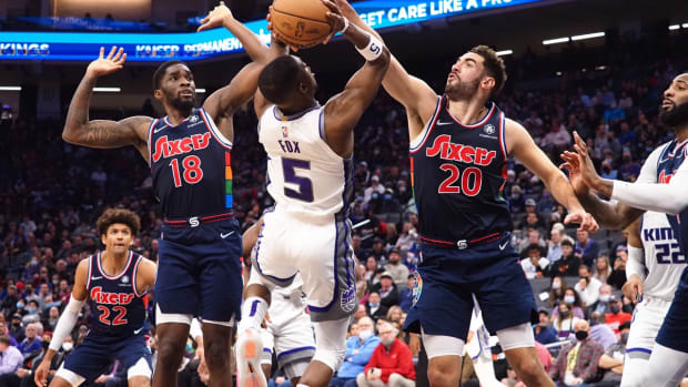 Nov 22, 2021; Sacramento, California, USA; Sacramento Kings guard De'Aaron Fox (5) shoots the ball between Philadelphia 76ers guard Shake Milton (18) and forward Georges Niang (20) during the fourth quarter at Golden 1 Center. Mandatory Credit: Kelley L Cox-USA TODAY Sports